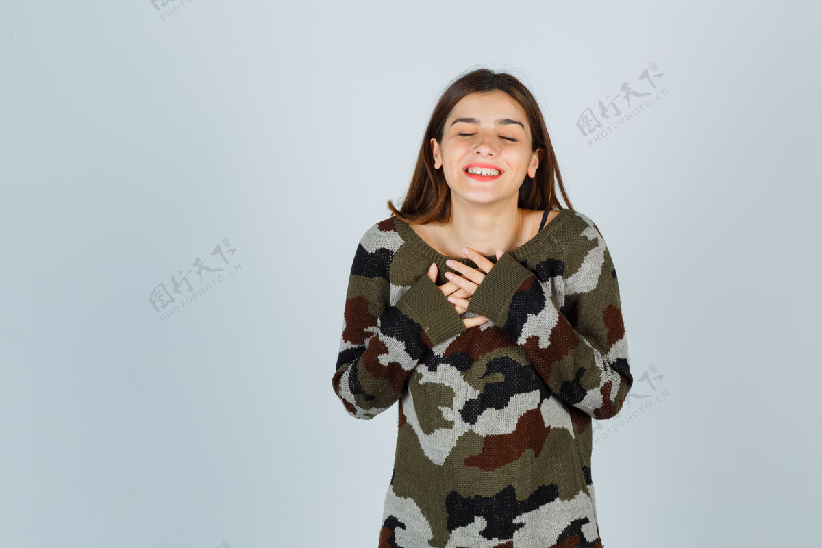 人穿着毛衣 裙子 手放在胸前的年轻女士看起来很快乐电话快乐肖像