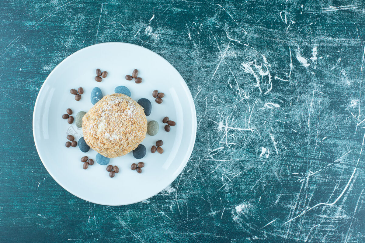 酿造一盘松鼠蛋糕 糖果和咖啡豆放在蓝色的盘子里岩石甜点糖