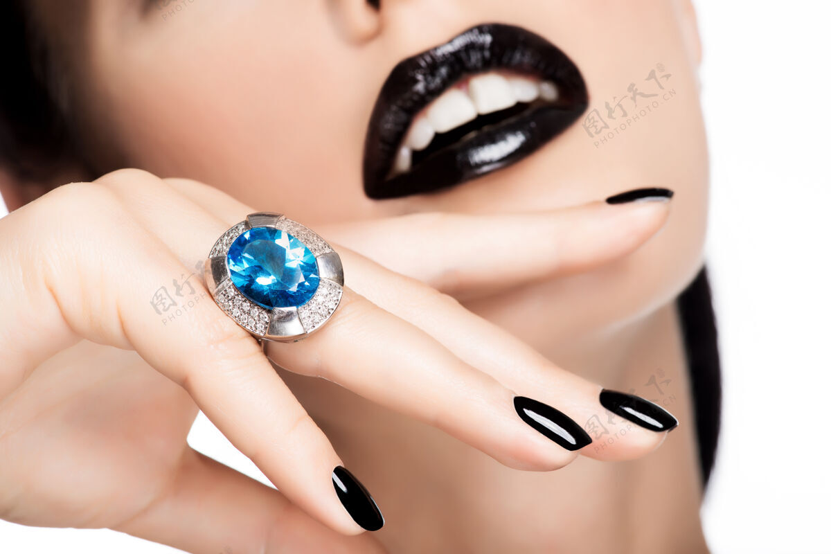 指甲一个女人的嘴唇和指甲被涂成亮黑色的宏观照片魅力手Bijouterie
