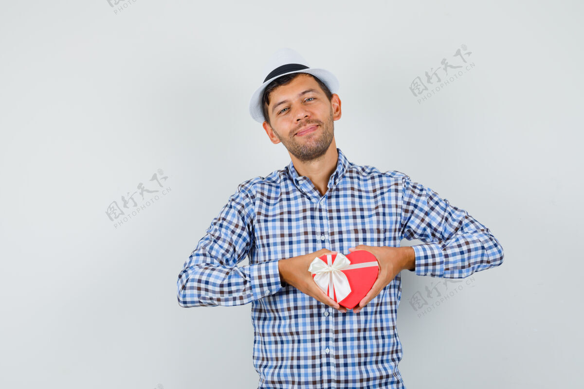 帅气一个穿着格子衬衫 戴着帽子的年轻人展示着礼物盒 看上去很高兴年轻前面快乐