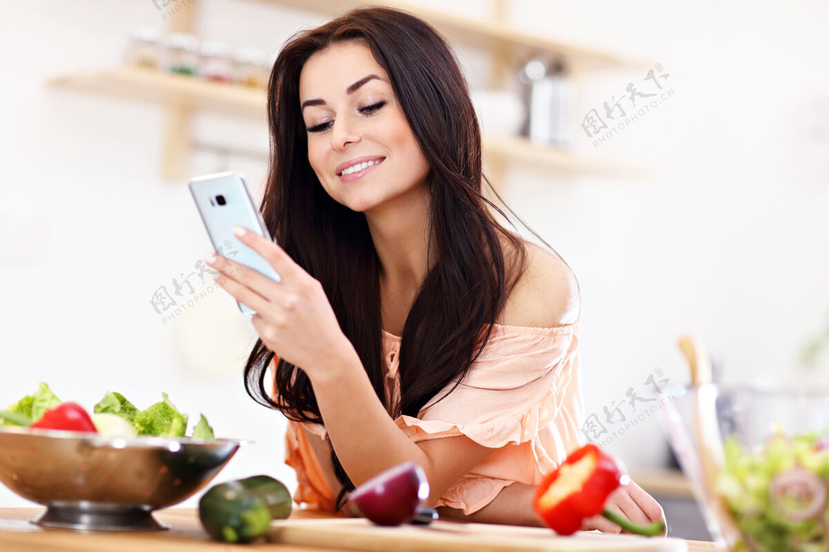 女性现代厨房里的快乐女人洋葱电话蔬菜