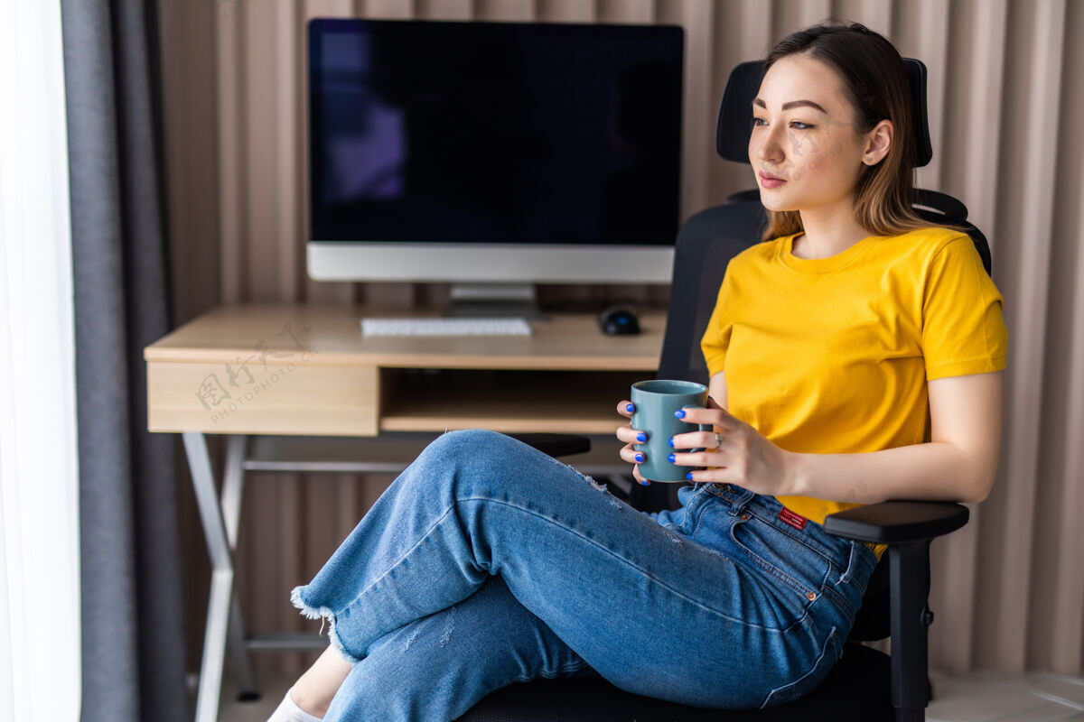 亚洲人拿着咖啡杯在家庭办公室工作的年轻女人商业科技在线
