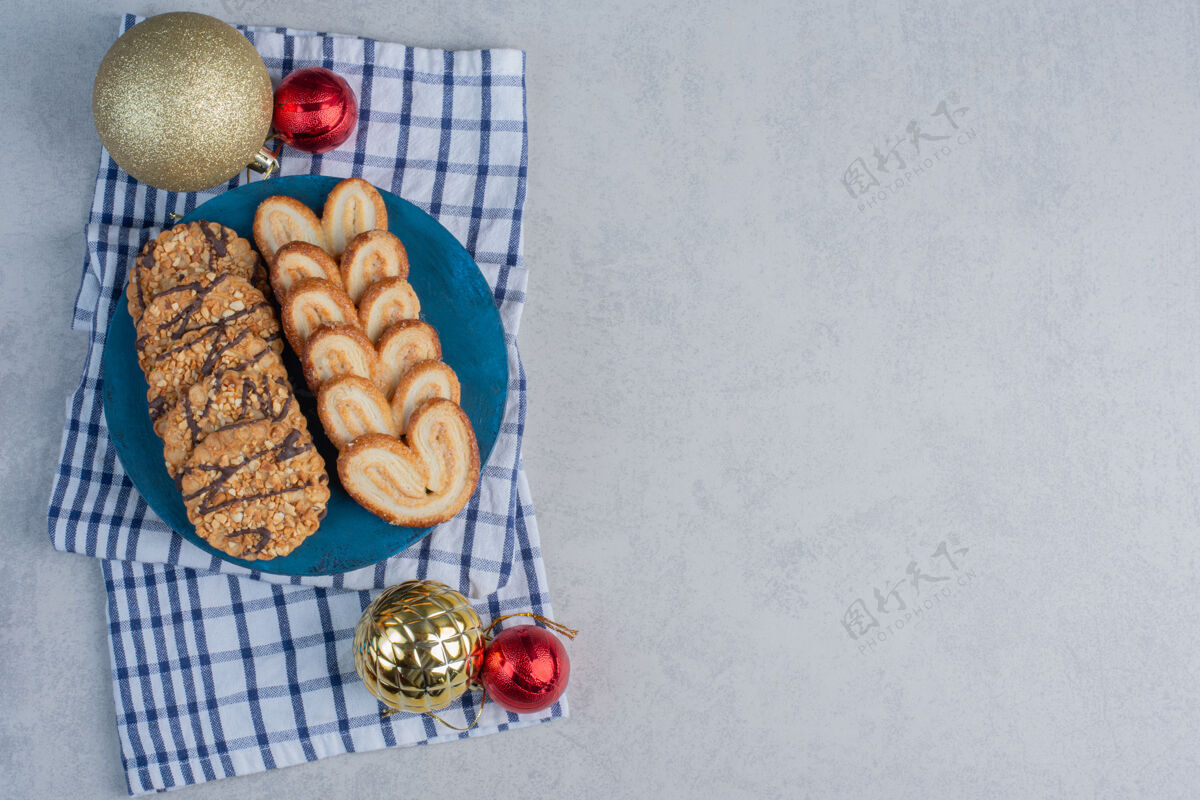 片状一排排饼干放在蓝色的木板上 旁边是放在大理石表面毛巾上的圣诞饰品美味糖毛巾