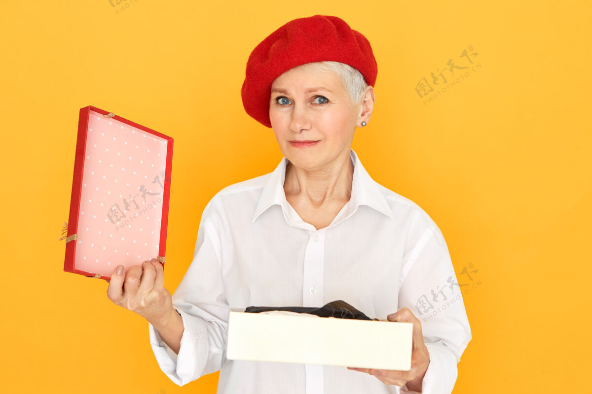 拆箱悲伤沮丧的成年退休女性肖像 戴着红色贝雷帽 在情人节打开礼物打开情人节赠送