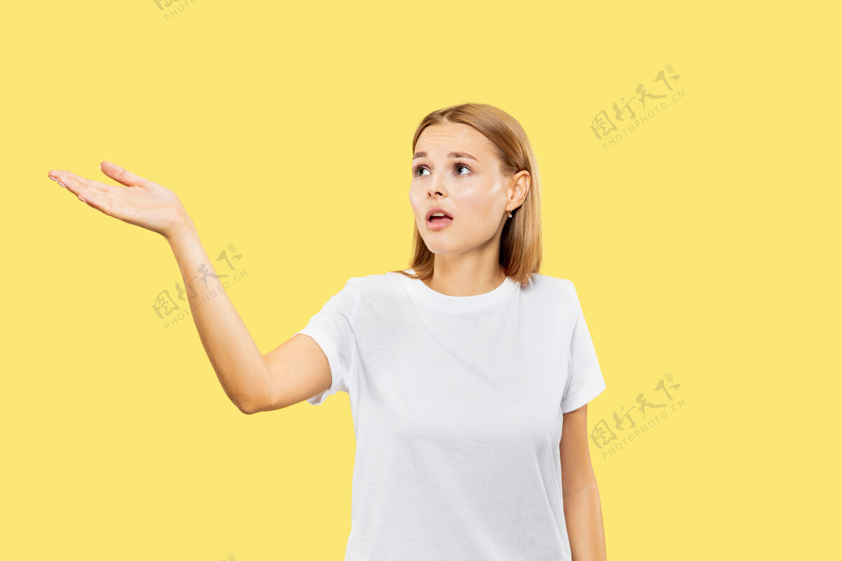年轻黄色工作室背景上的白人年轻女子半身像穿着白衬衫的漂亮女模特人类情感的概念 面部表情展示一个空的空间或邀请公司行政金发