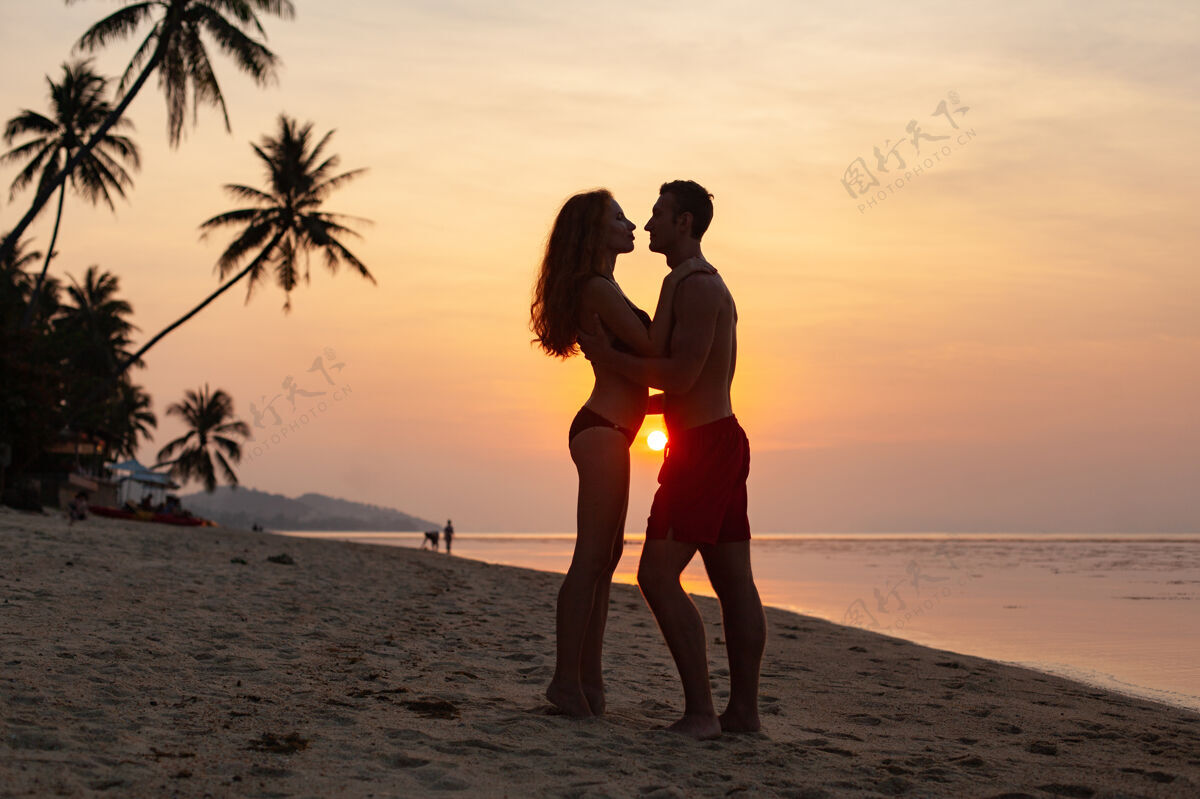 关系年轻性感浪漫的情侣在夕阳下相爱 在夏日的沙滩上快乐地穿着泳衣一起玩海滩男朋友人