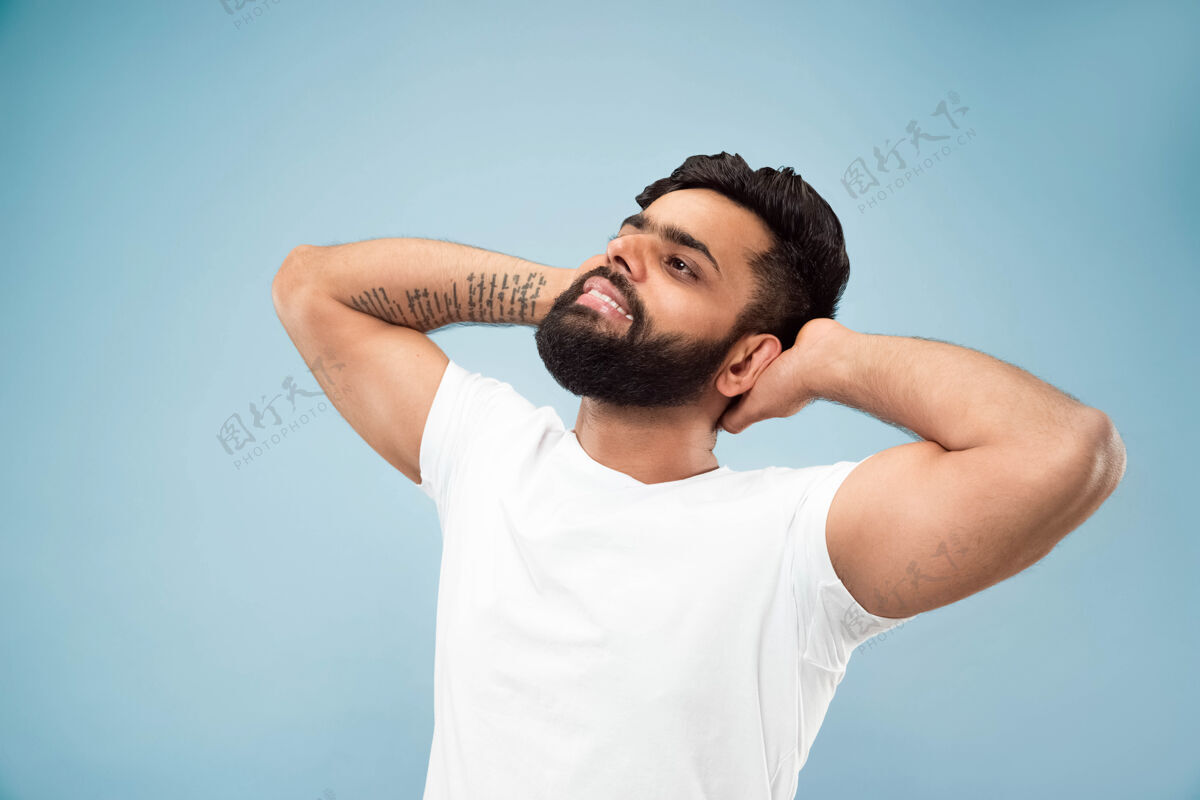 胡须蓝色背景上穿着白衬衫的印度年轻人的半身特写肖像人类情感 面部表情 广告概念负面空间休息 放松 看起来平静高管工作顺序