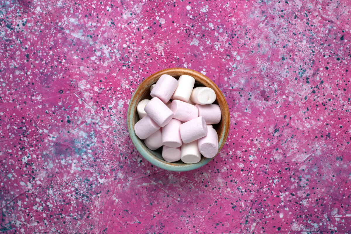 里面甜美可口的棉花糖顶视图 在粉红色的表面上的圆形锅里形成一点蛋白酥皮桌圆