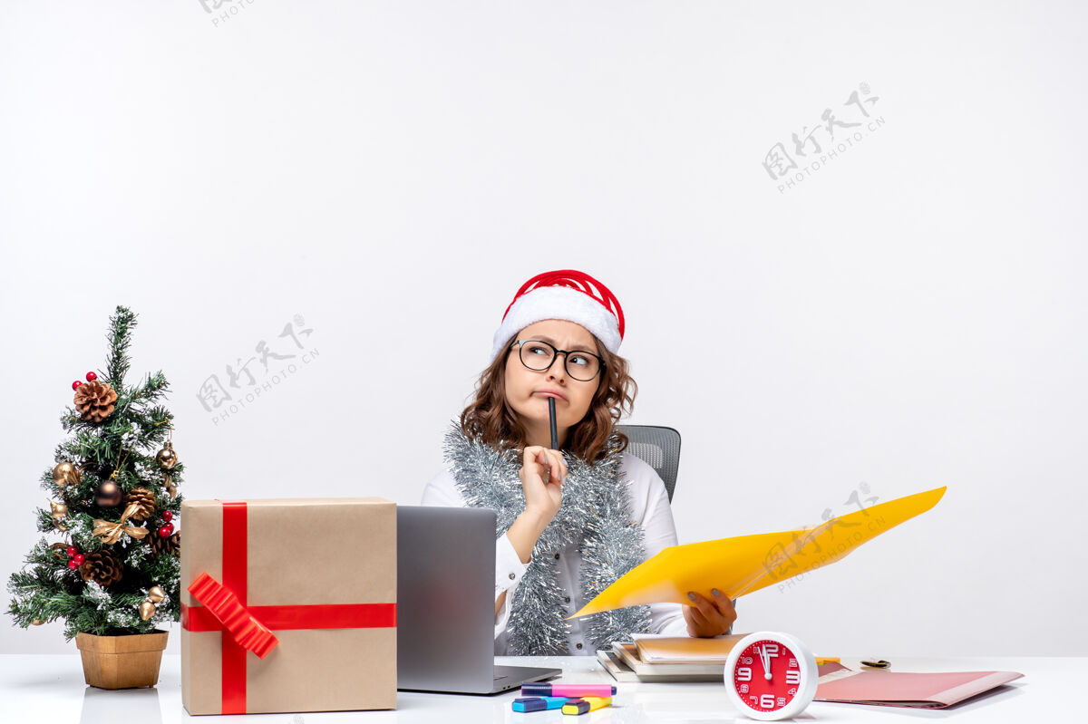 笔记本电脑前视图年轻的女工人坐在她的地方和白色背景上的文件工作文件工作前面