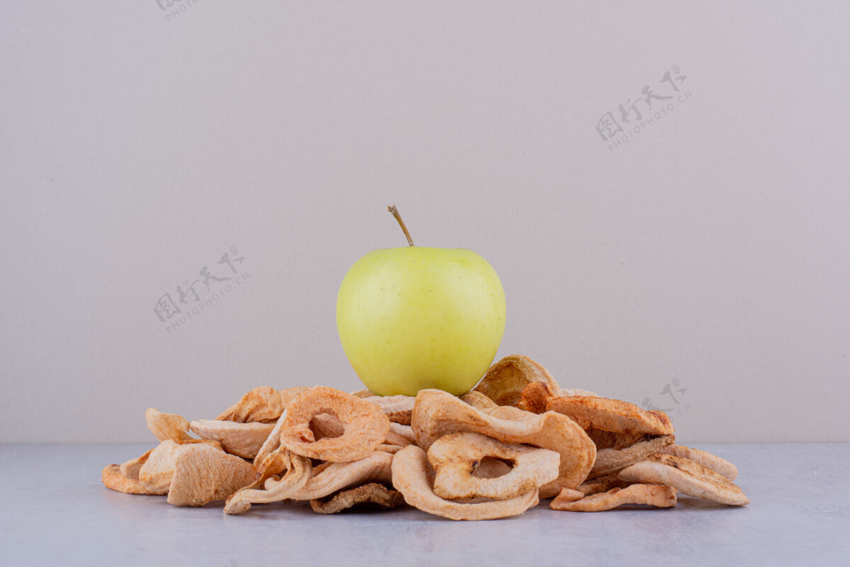 美味青苹果坐在一堆白底干苹果片上苹果水果美味