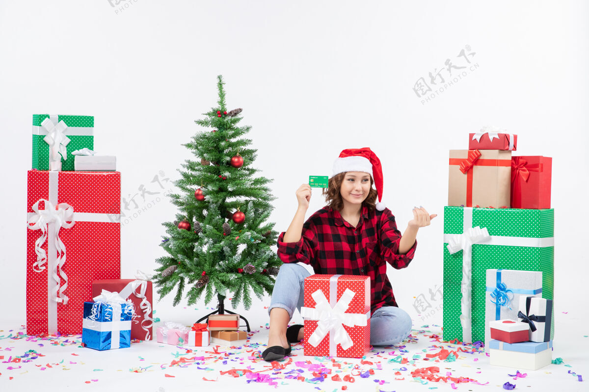快乐正面图：年轻女子围坐在白墙上 手里拿着绿色的银行卡礼物快乐人
