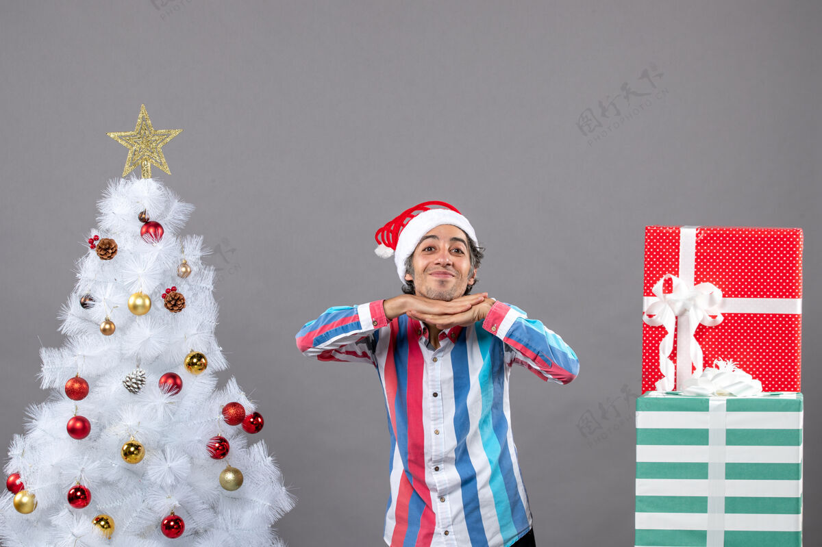 下巴前视图幸福的帅哥把手放在他的下巴附近白色圣诞树人灰圣诞