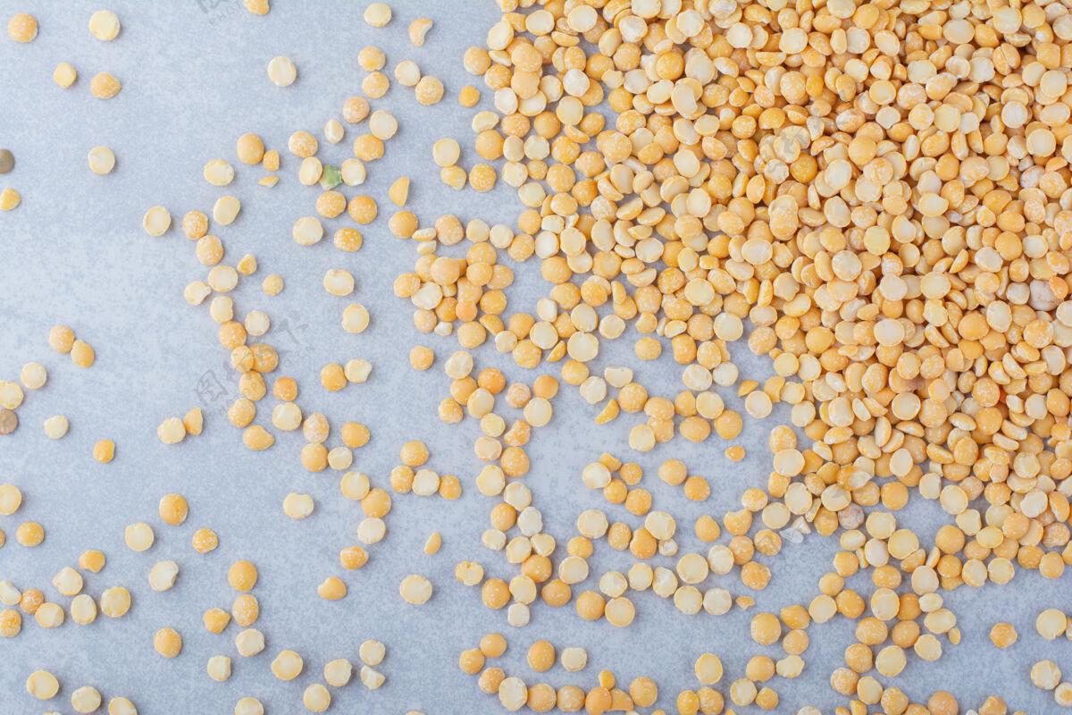有机的黄色小扁豆杂乱地散落在大理石背景上天然的料理谷物