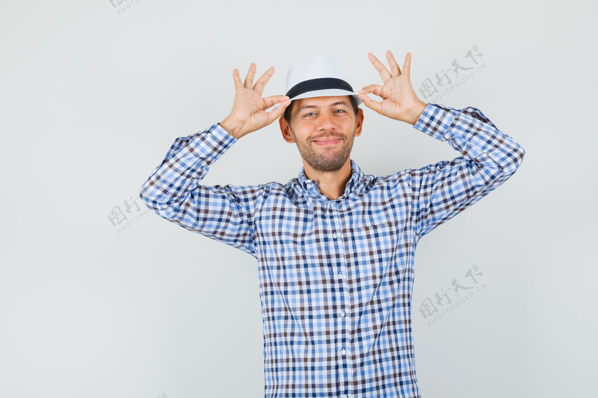 站立一个穿着格子衬衫的年轻男人拿着他的帽子 看起来很快乐成人人类肖像