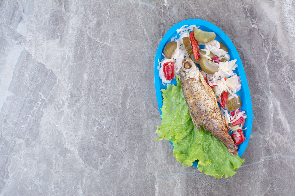 卷心菜青鱼和腌菜放在蓝色盘子里小吃发酵海鲜