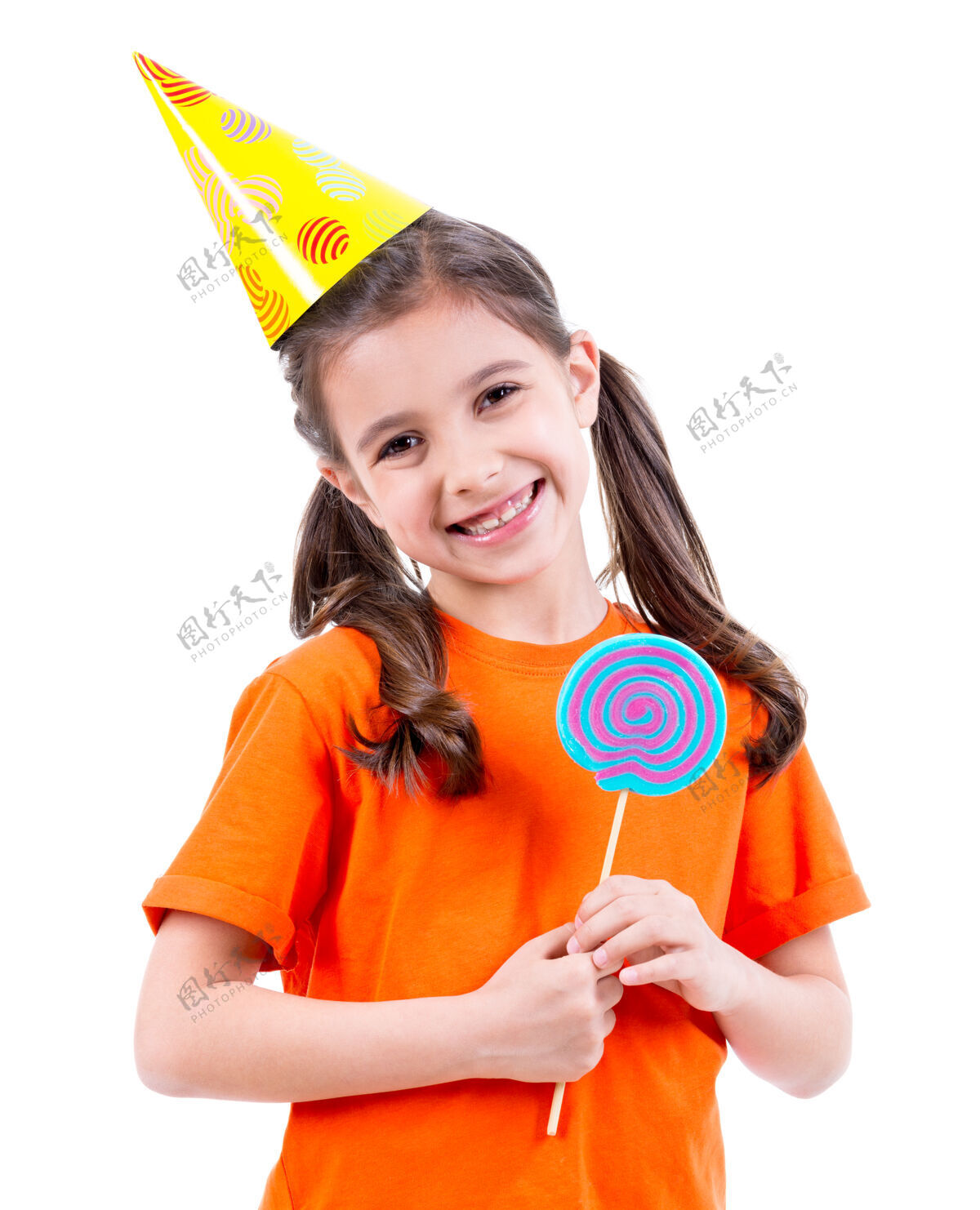 甜食身着橙色t恤 戴着彩色糖果的派对帽的可爱小女孩的肖像-白色隔离聚会T恤小