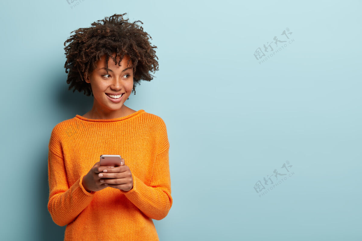 满意照片中快乐的非洲裔美国妇女在现代手机上输入短信 享受良好的互联网连接旁边小玩意互联网
