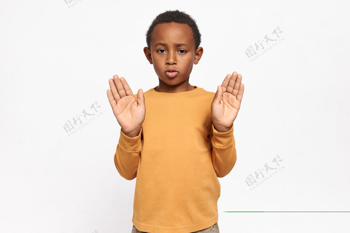 种族穿着运动衫的严肃自信的非洲裔美国小学生的肖像 他伸出双手 手掌张开 做出停止的手势保护手势禁止