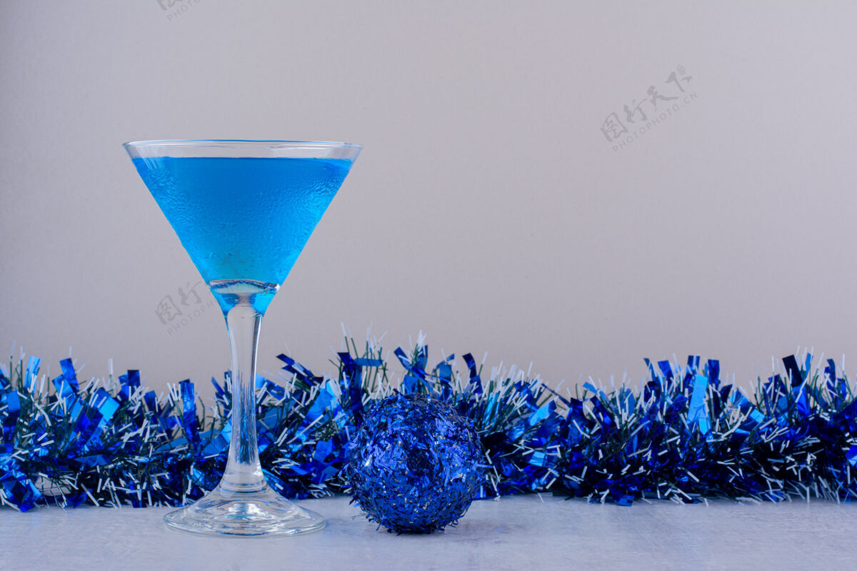 构图鸡尾酒杯旁边是白色背景上的蓝色圣诞装饰舞会饮料花环