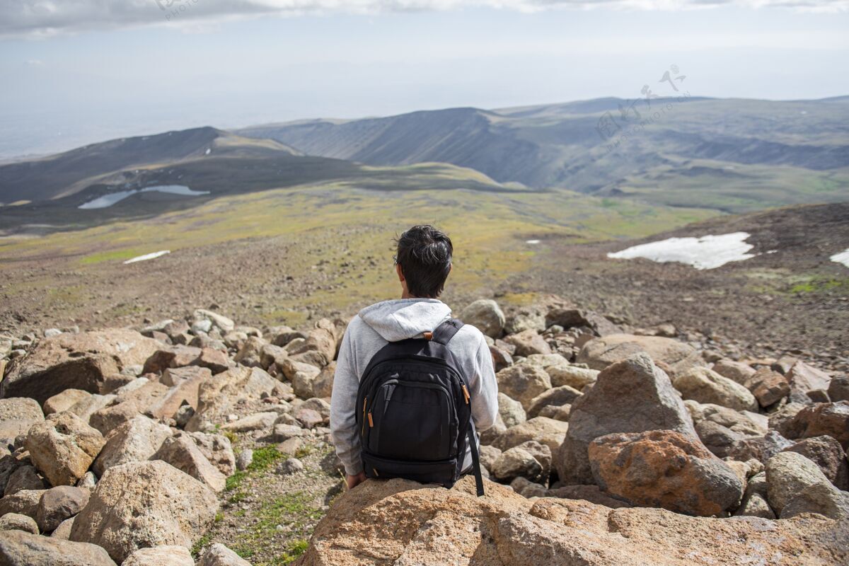 休息选择性聚焦拍摄一个人坐在岩石上美丽的山景岩石天空环境