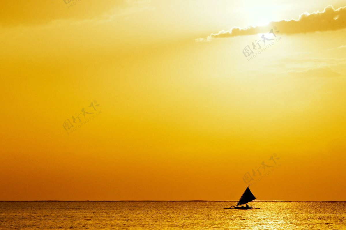 港口海边有金色的夕阳和帆船在海洋中央船波浪热带