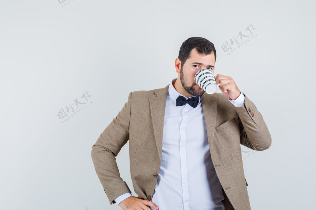 帅气年轻男性穿着西装 手放在腰上喝咖啡 正面视图人男人腰身