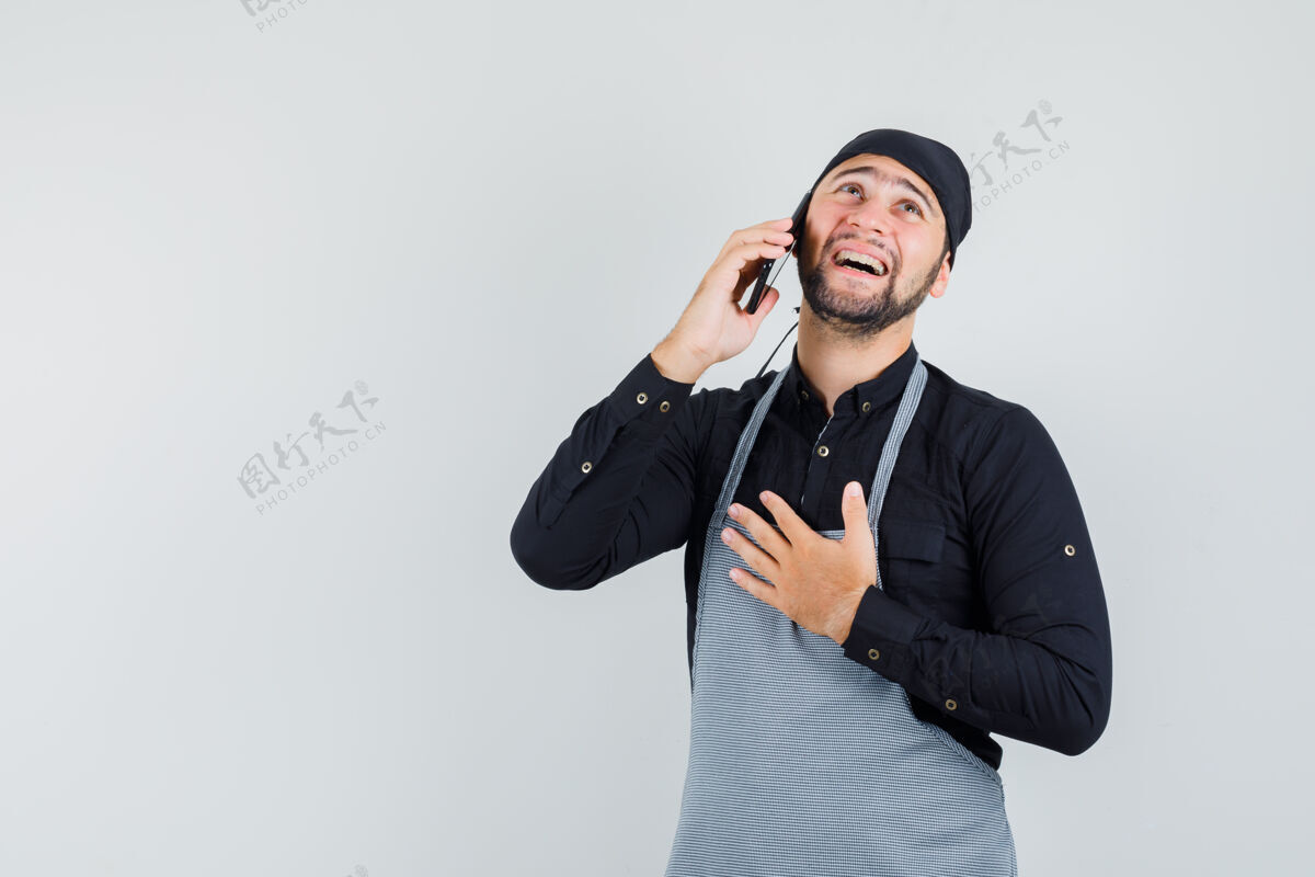 电话男厨师穿着衬衫 围着围裙讲着手机 看上去兴高采烈 眼前一亮职业手机人