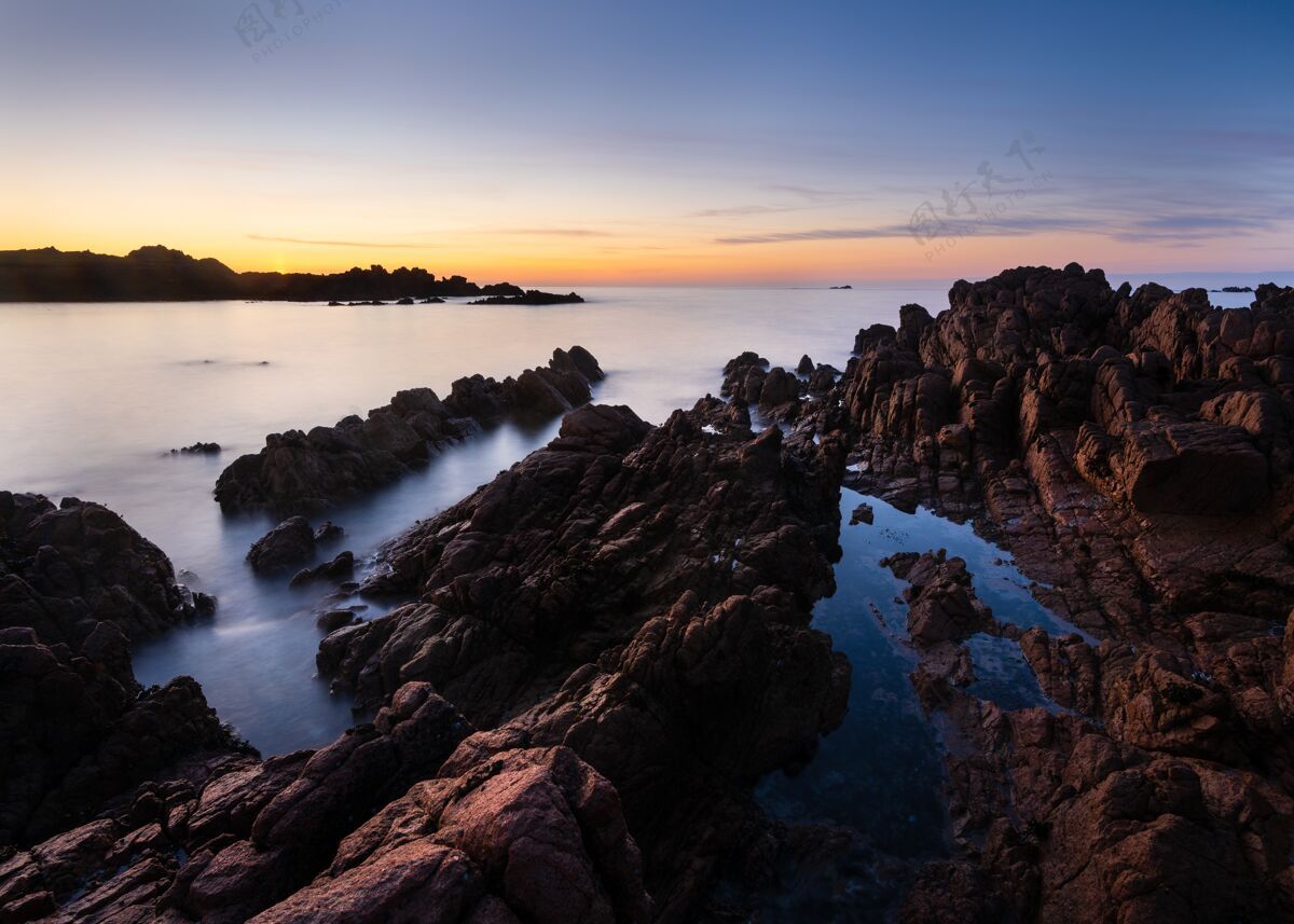 水日落时岩石海滩的惊人镜头场景岩石阳光
