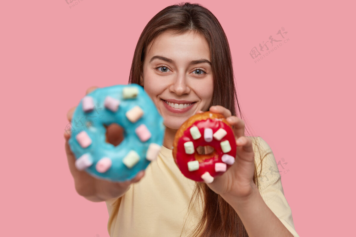 面包店美女照片拿着好吃的甜甜圈 建议品尝 积极微笑 有吸引力的样子高兴人类拿着