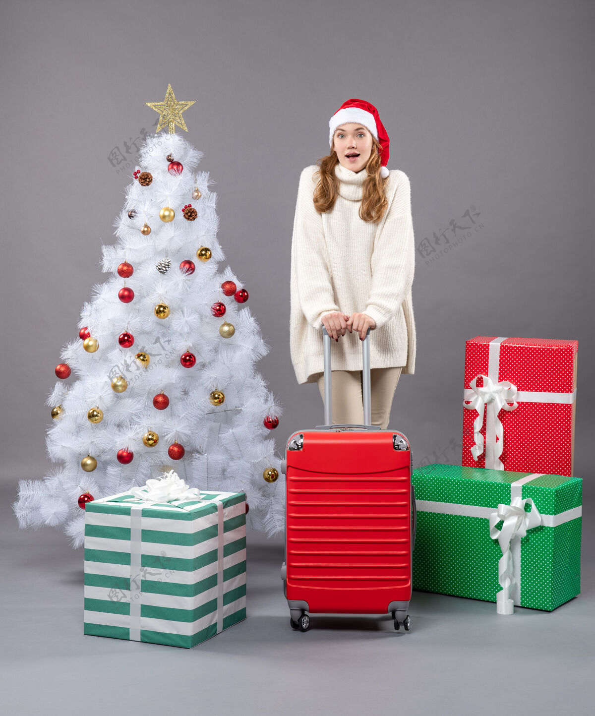 惊喜圣诞女孩前视图惊讶的圣诞节女孩拿着旅行箱站在圣诞树附近庆祝快乐站着