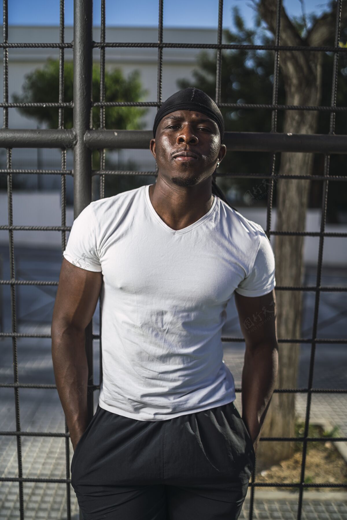 围栏一个穿着白衬衫的非洲裔美国男性斜靠在栅栏上的垂直镜头教练自信运动
