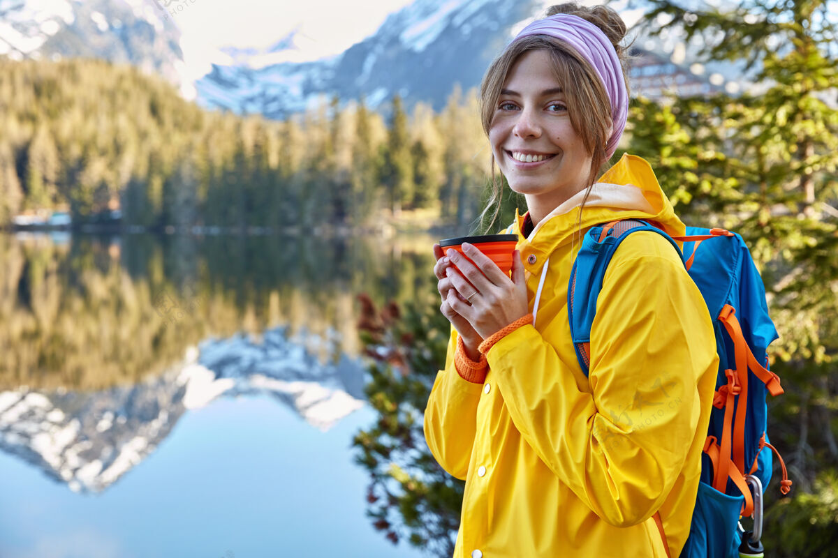 咖啡快乐美丽的女游客在山上度假 用一次性杯子喝咖啡女性湖泊海岸