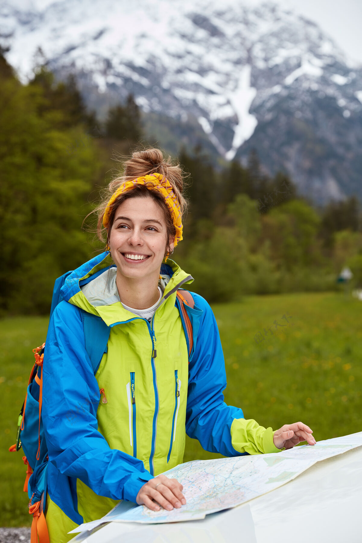 山脉积极的白人女旅行者站在地图附近 研究路线 头上戴着黄色围巾 休闲的休闲长裤发现方向背包