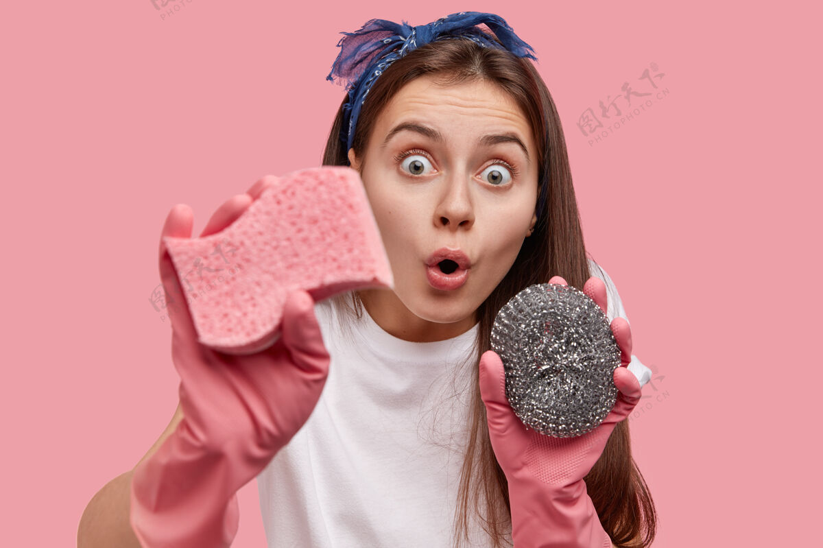惊呆惊讶的黑发女士拿着清洁工具 已经瞪大了眼睛 惊讶地看到了很多污垢手套卫生管家