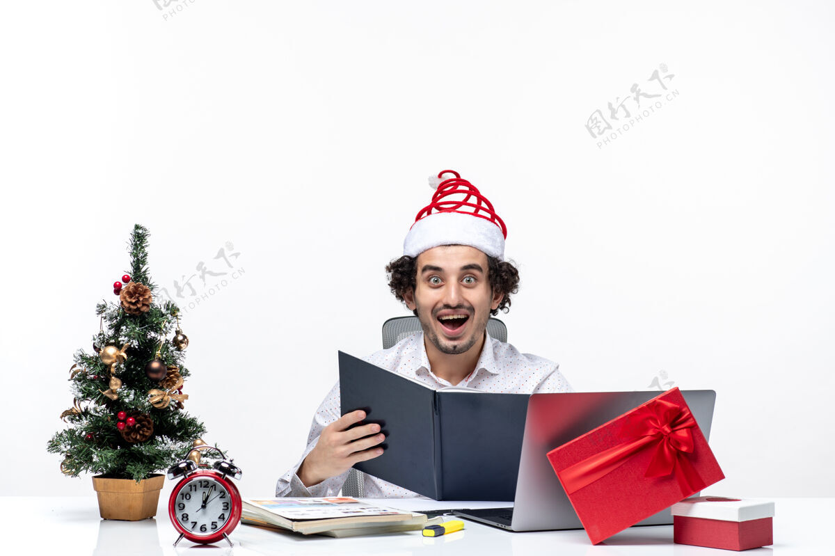 圣诞老人惊讶兴奋的积极的年轻商人与有趣的圣诞老人帽子检查文件中的信息在白色背景的办公室电脑兴奋女商人