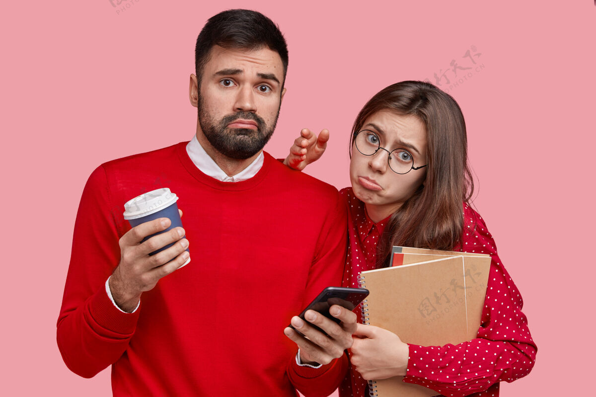 学习不高兴的欧洲女士和男友一起摆姿势 穿同一种颜色的衣服喝咖啡休息 使用现代智能手机进行在线交流知识毛衣文学