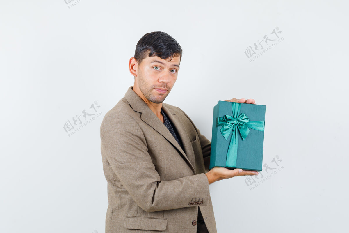 肖像年轻男性手持蓝色礼盒 身穿灰棕色夹克 看上去自信满满 正面照休闲时尚成人