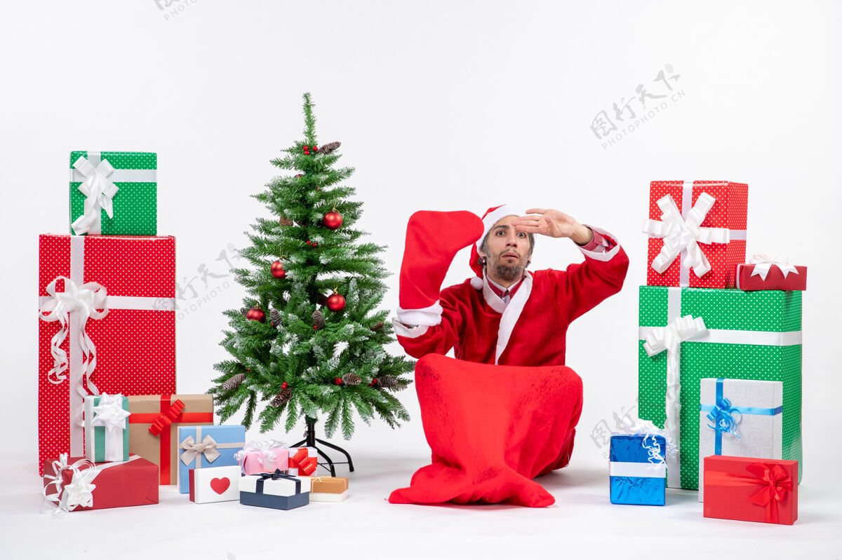圣诞老人新年的心情与圣诞老人坐在地上 穿圣诞袜子附近的礼物和装饰圣诞树上的白色背景礼物圣诞老人礼物
