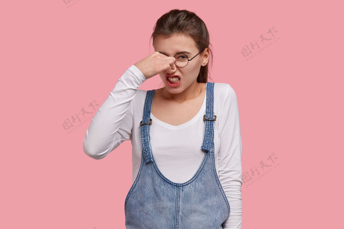 阴性不开心不满意的女人皱着眉头 因为难闻的气味捏着鼻子 咬牙切齿面部气味厌恶