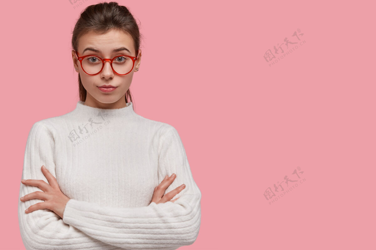 眼镜漂亮女人的摄影棚镜头以专注的表情看 双手交叉 穿套头衫外观个人斯特恩