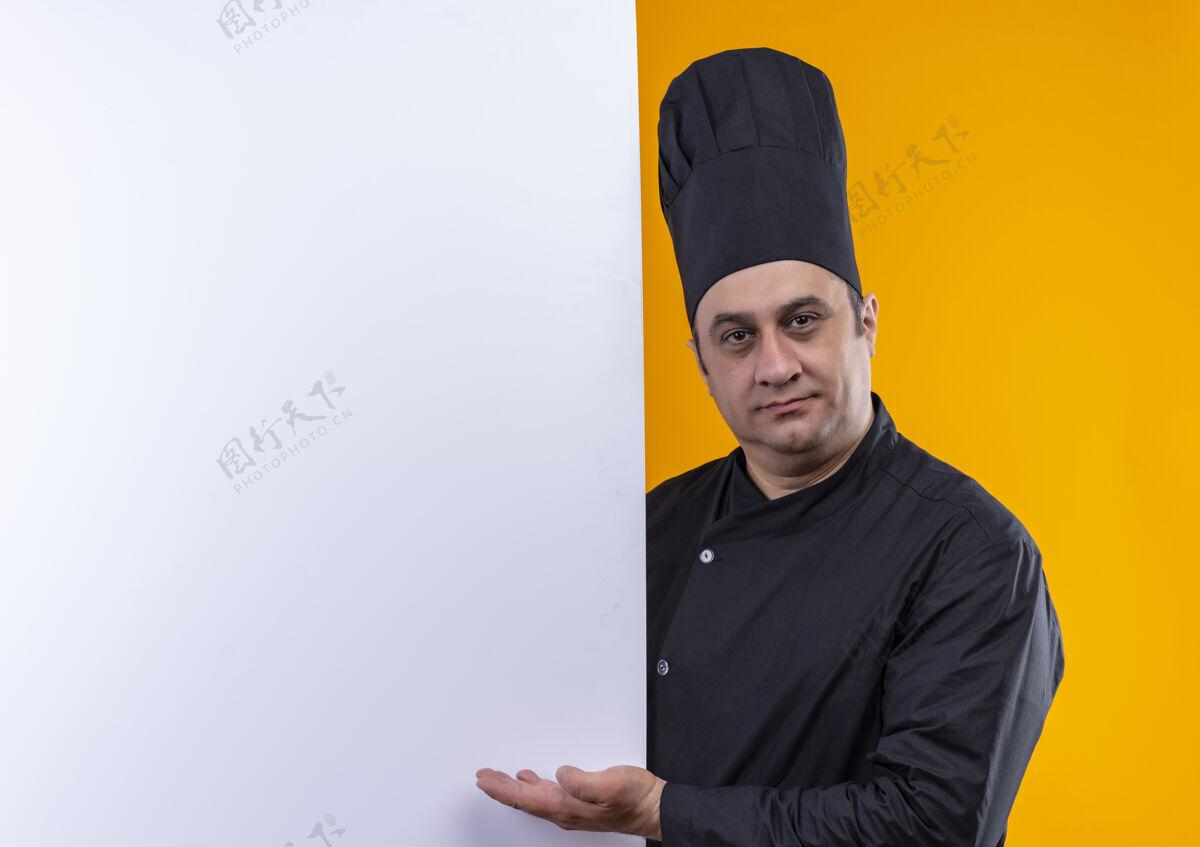 制服身着厨师制服的中年男厨师在黄色墙壁上展示白色墙壁和复制空间展示男中年