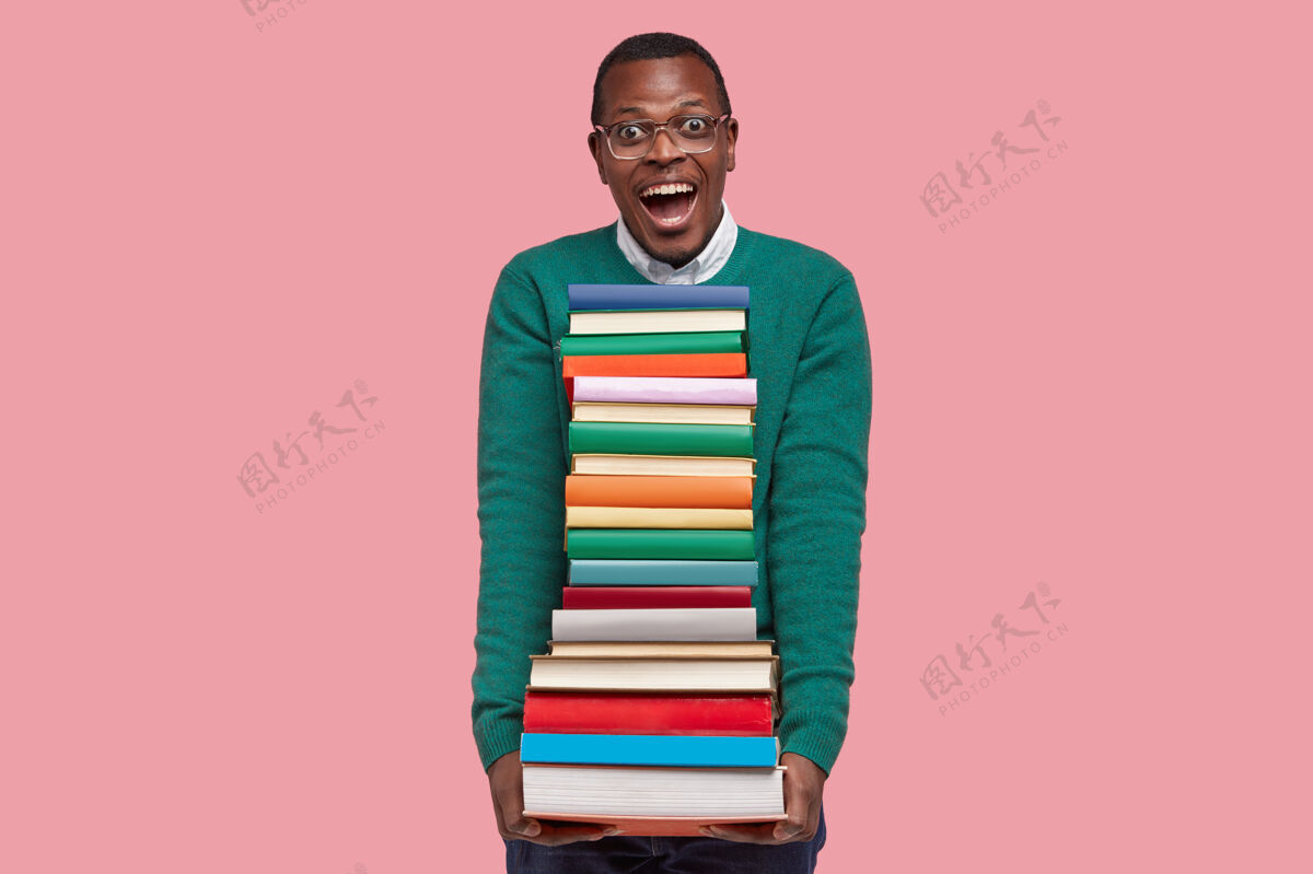 男性帅气的黑人青年在粉色的画室背景下摆姿势 拿着课本 多读书 备课个性高兴文学