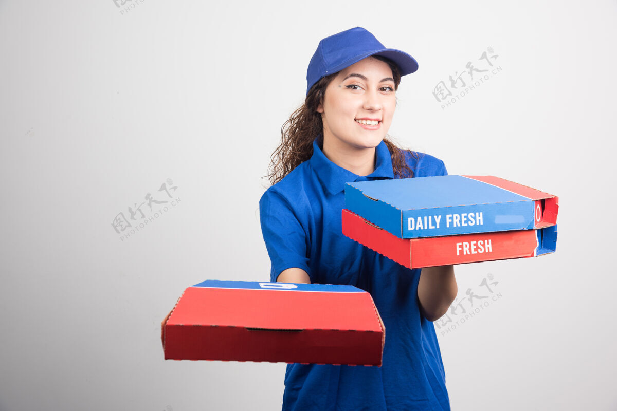 帽子送比萨饼的女孩拿着三个白色背景的盒子高质量的照片美味用餐披萨