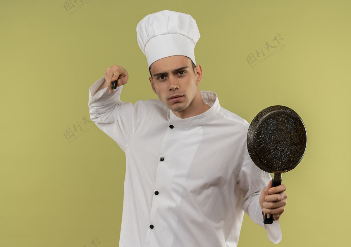 刀严格的年轻男厨师穿着厨师制服 手里拿着炒锅刀手养平底锅