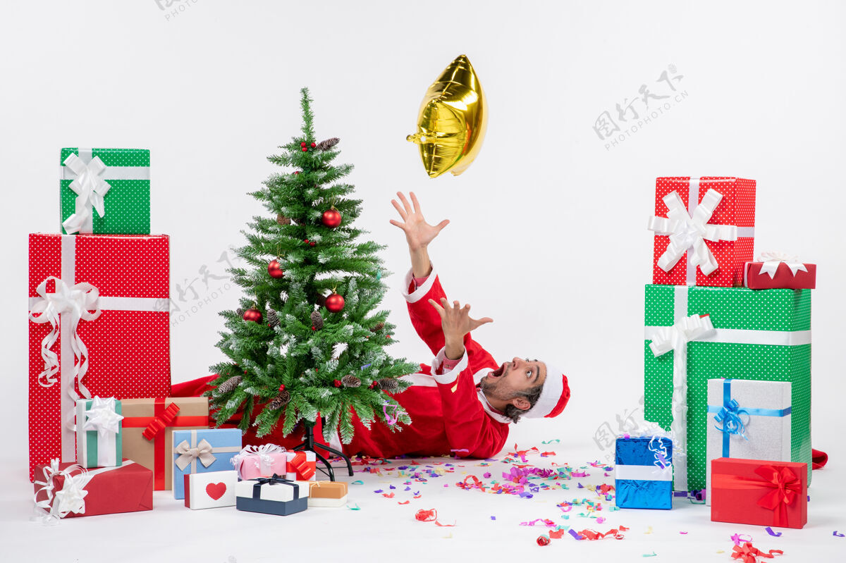 不同圣诞心情与年轻的圣诞老人躺在圣诞树旁边的礼物在不同颜色的白色背景图片圣诞老人季节年轻