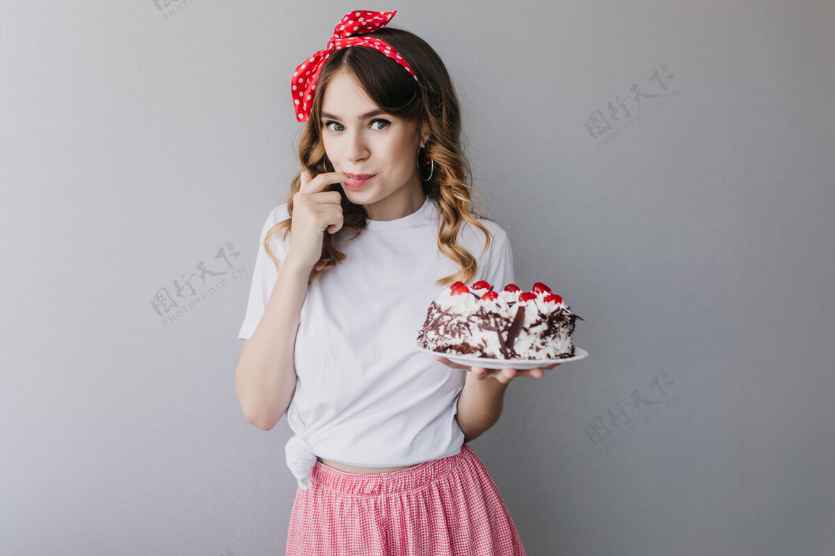 水果灵感女孩与波浪头发品尝生日蛋糕迷人的女模特与馅饼摆姿势女士模特配饰