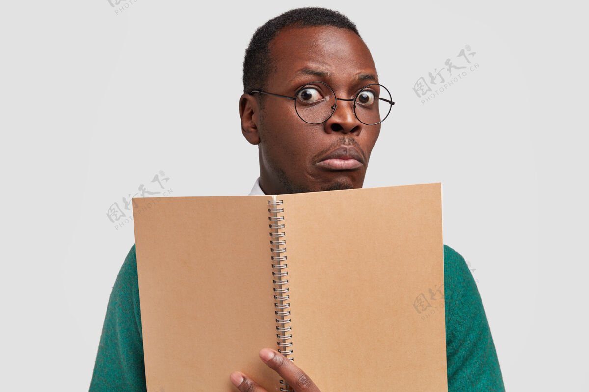 惊讶麻木的黑人学生特写镜头来上课 拿着写信息的螺旋笔记本 戴着眼镜拿着记事本作业