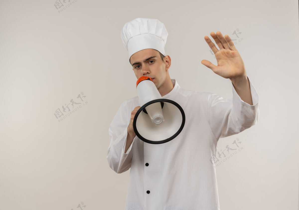 穿身穿厨师制服的年轻男厨师在扬声器上讲话 手伸向隔离的白色墙壁 留有复印空间手厨师厨师