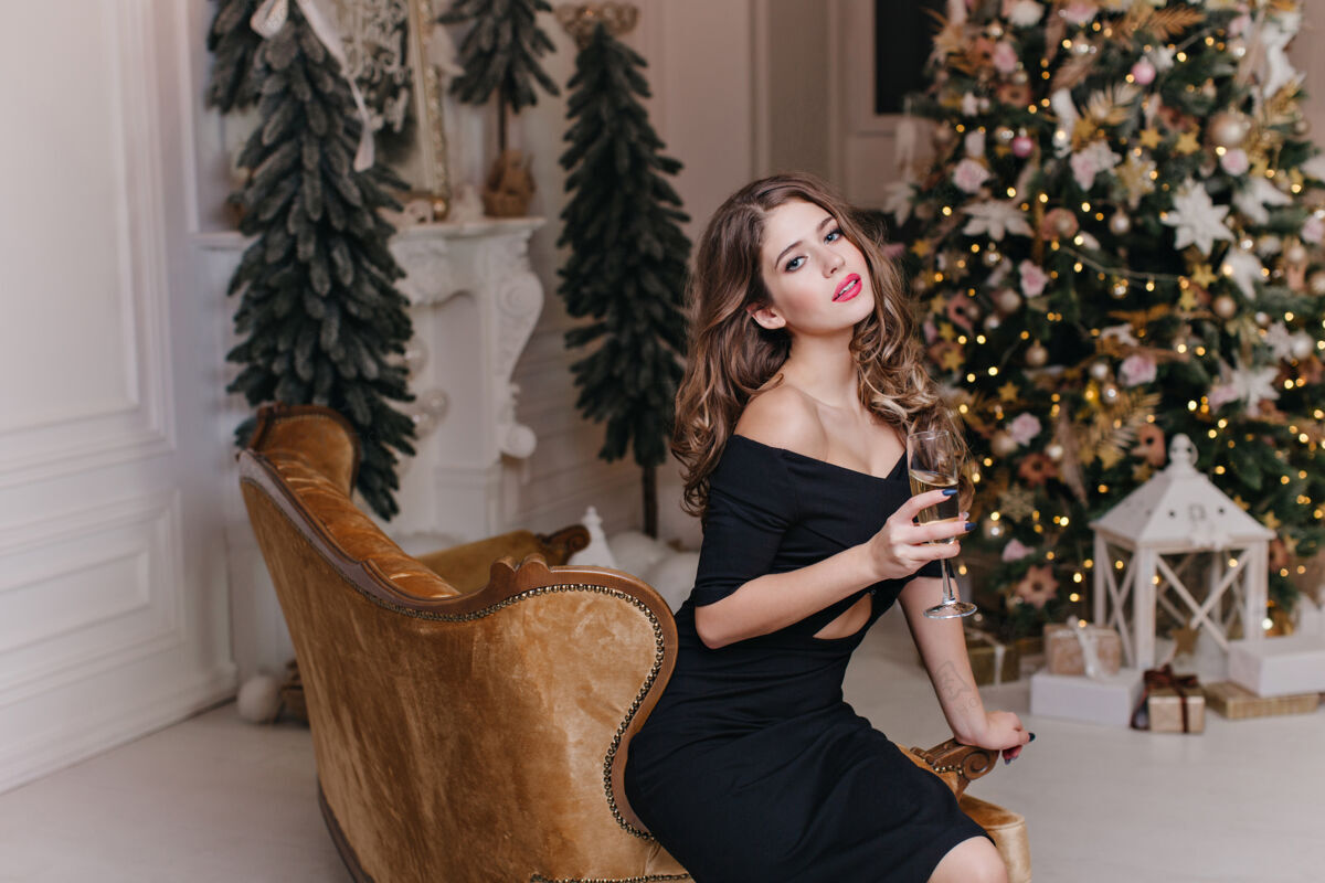 时尚公寓里优雅 昂贵的新年气氛造就了优雅 迷人的黑发女郎 明亮的双唇 捧着一杯起泡酒的美妙心情休闲乐趣享受